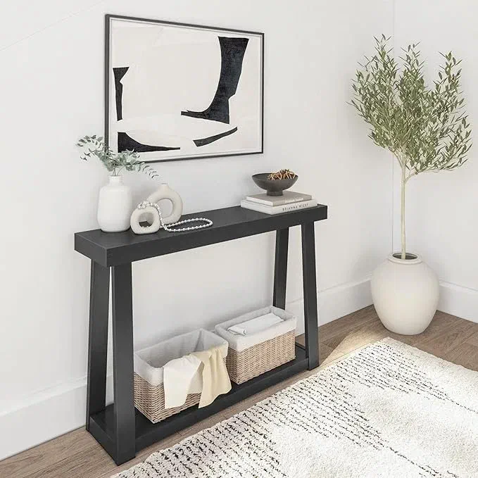 Black wood console table styled with vases and framed art, woven storage baskets tucked on the lower shelf