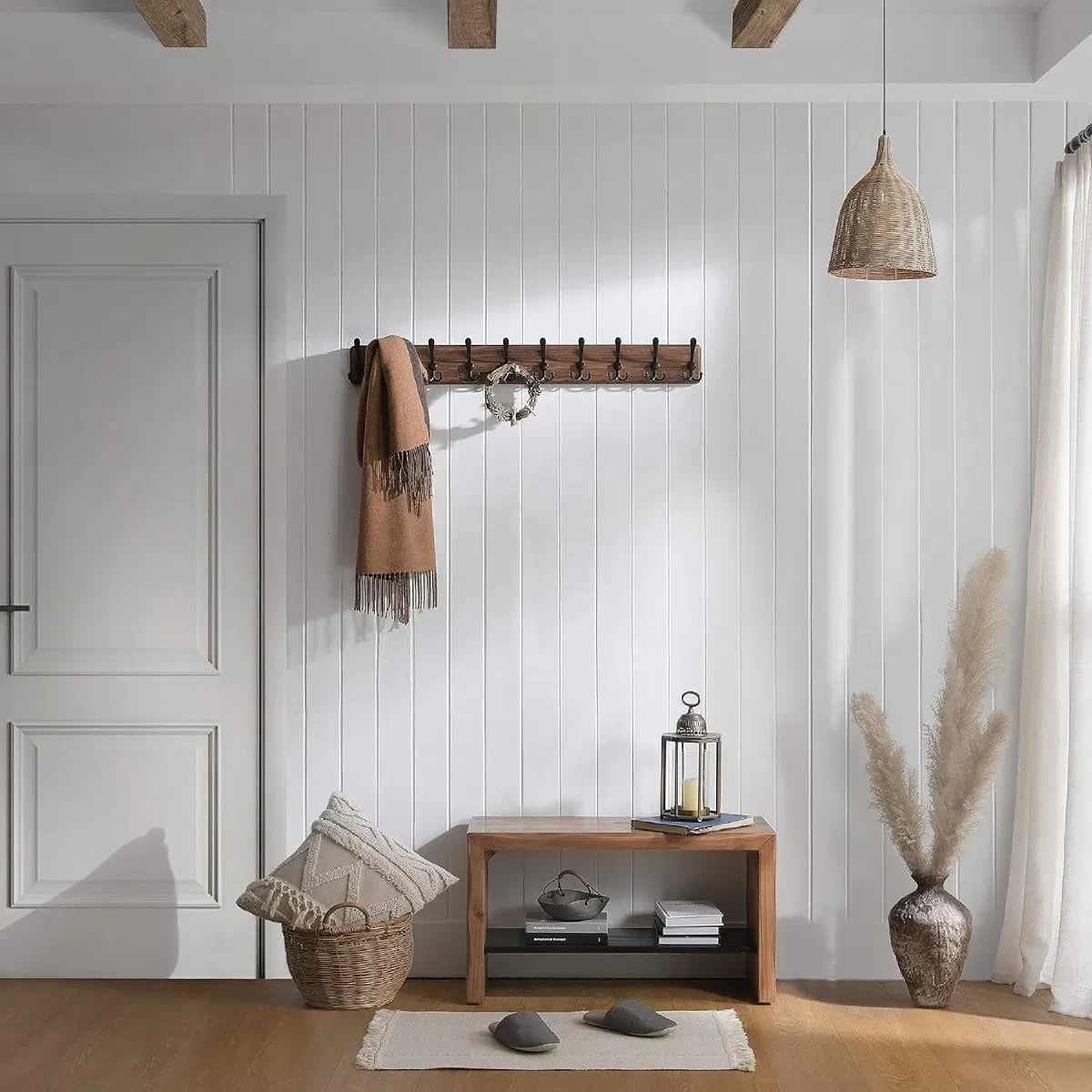 Rustic wall-mounted coat rack with a wool scarf and small wreath draped over the hooks, above a wooden entryway bench