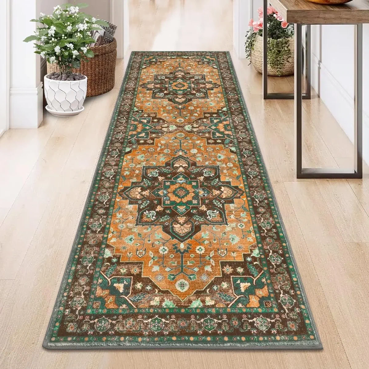 Ornate orange and green medallion-pattern runner rug laid down a wood-floored hallway between potted plants