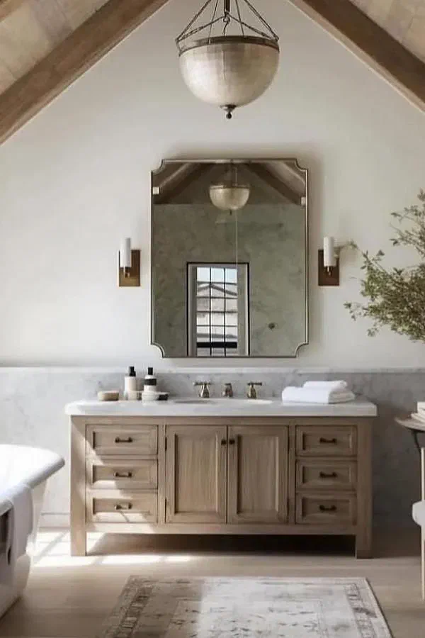 Farmhouse bathroom with a light wood vanity, marble countertop, large mirror, and exposed wooden ceiling beams.