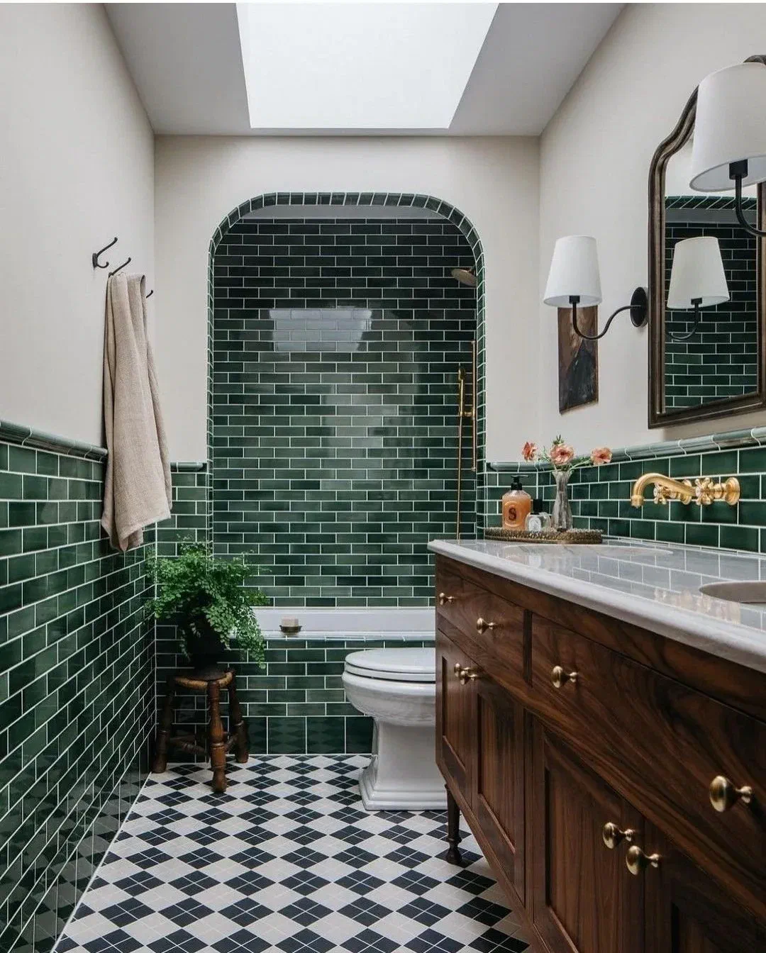 Bathroom with bold dark green subway tiles, black and white patterned floor, and a dark wood vanity.