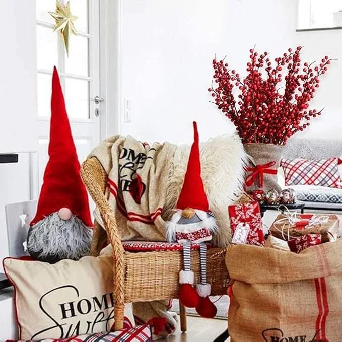 Bundle of artificial red berry stems in a burlap-wrapped vase beside plaid pillows and gnome decorations