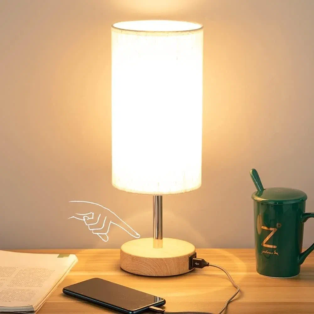 Modern touch control bedside lamp with wood base, white linen shade, and dual USB charging ports on nightstand