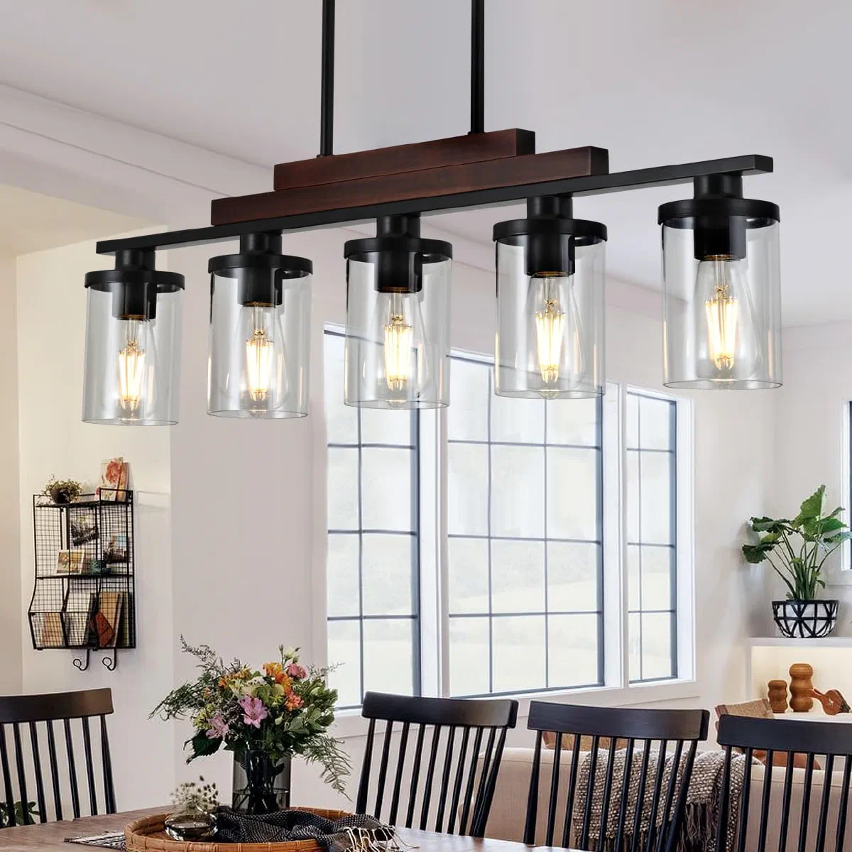 Rustic solid wood and matte black linear chandelier with clear glass shades over a long rectangular dining table