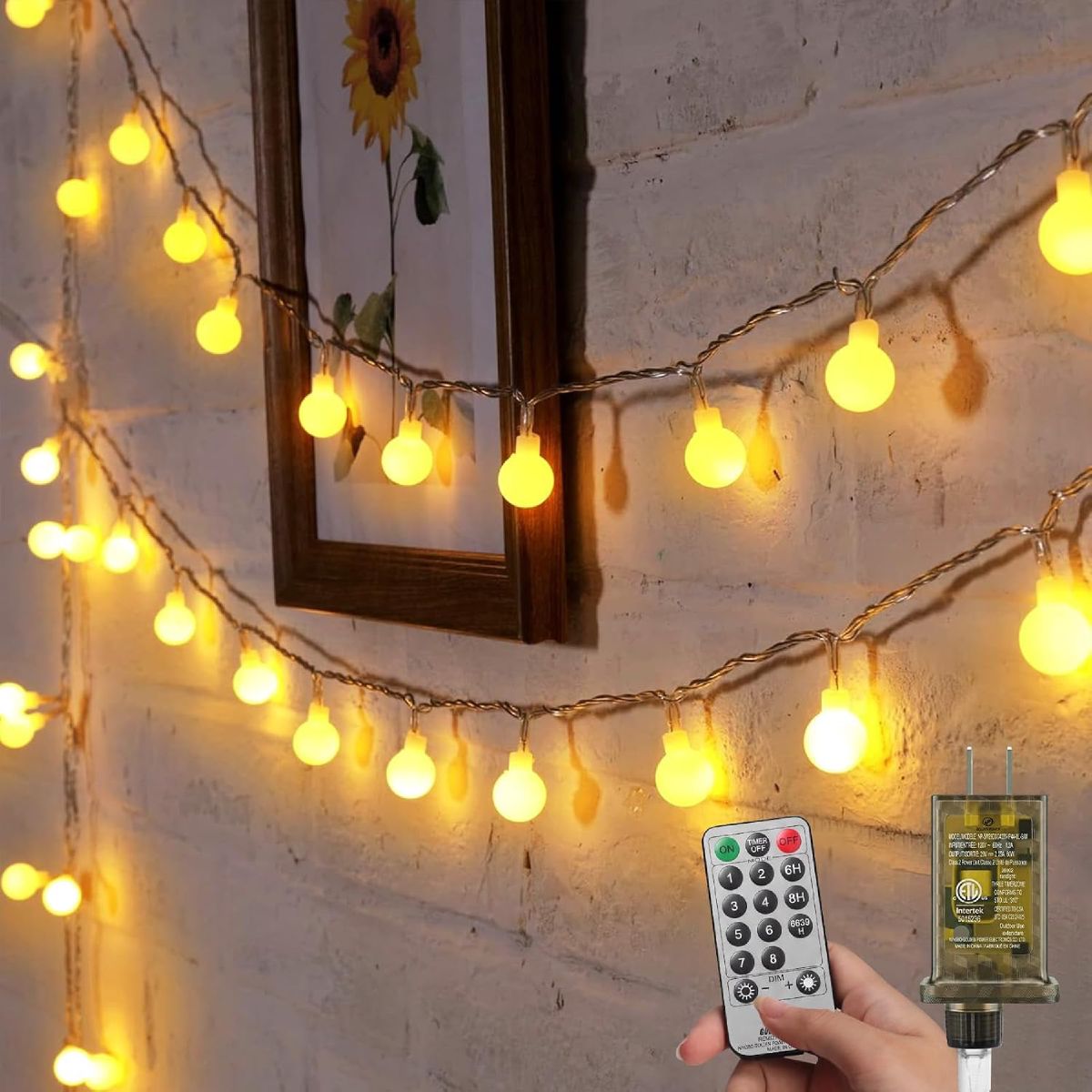 Minetom warm-white globe string lights draped across a brick wall around a mirror, with the included remote and plug