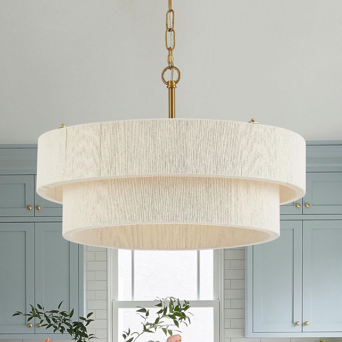 Two-tier hand-woven rattan boho pendant light with brass hardware, hanging over a kitchen island