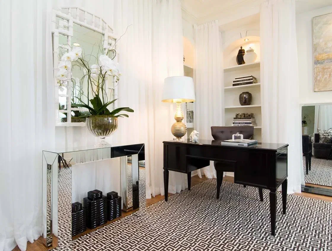 Home office with mirrors and light colors, showing how to make a room brighter. White curtains, mirror, and light walls reflect light.