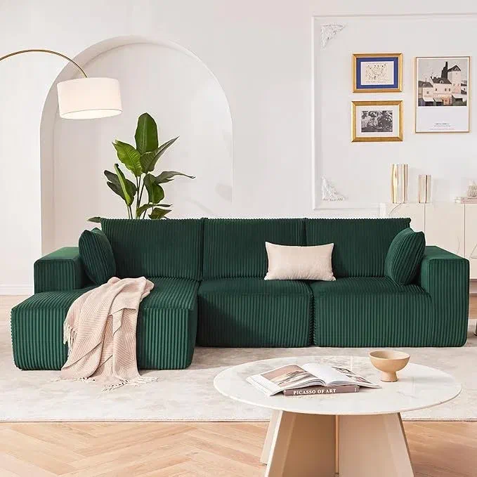 Dark green ribbed modular sectional sofa with a cream throw pillow, styled beneath a gallery wall of framed art