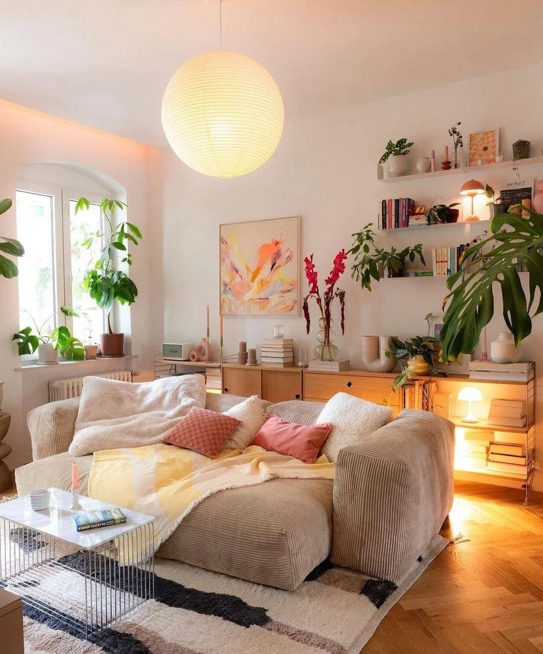 Cozy corduroy sectional piled with plush pillows and a knit throw under a large paper lantern pendant light