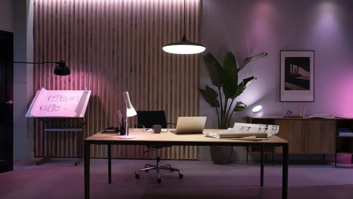 A stylish home office with modern desk lamp, pendant light, and ambient lighting in purple and white tones, creating a productive and comfortable workspace.